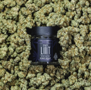 A Cannabis Jar Sitting in a Lot of Marijuana Buds